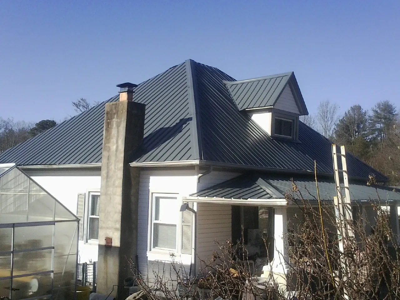 Dark blue standing seam metal roof on a white farmhouse with dormer — Slate & Tile Roof Repair by Roofing Brothers in Newton Falls
