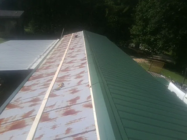 Old rusted panels beside newly installed green metal roofing — Wind Damage Roof Repair by Roofing Brothers in Newton Falls