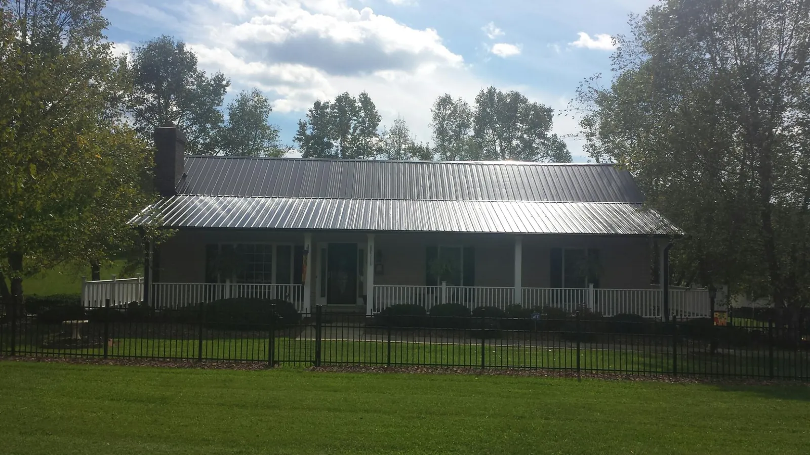 Gray metal roof on a brick ranch with a full width front porch — Gutter Guard Installation work by our crew in Newton Falls