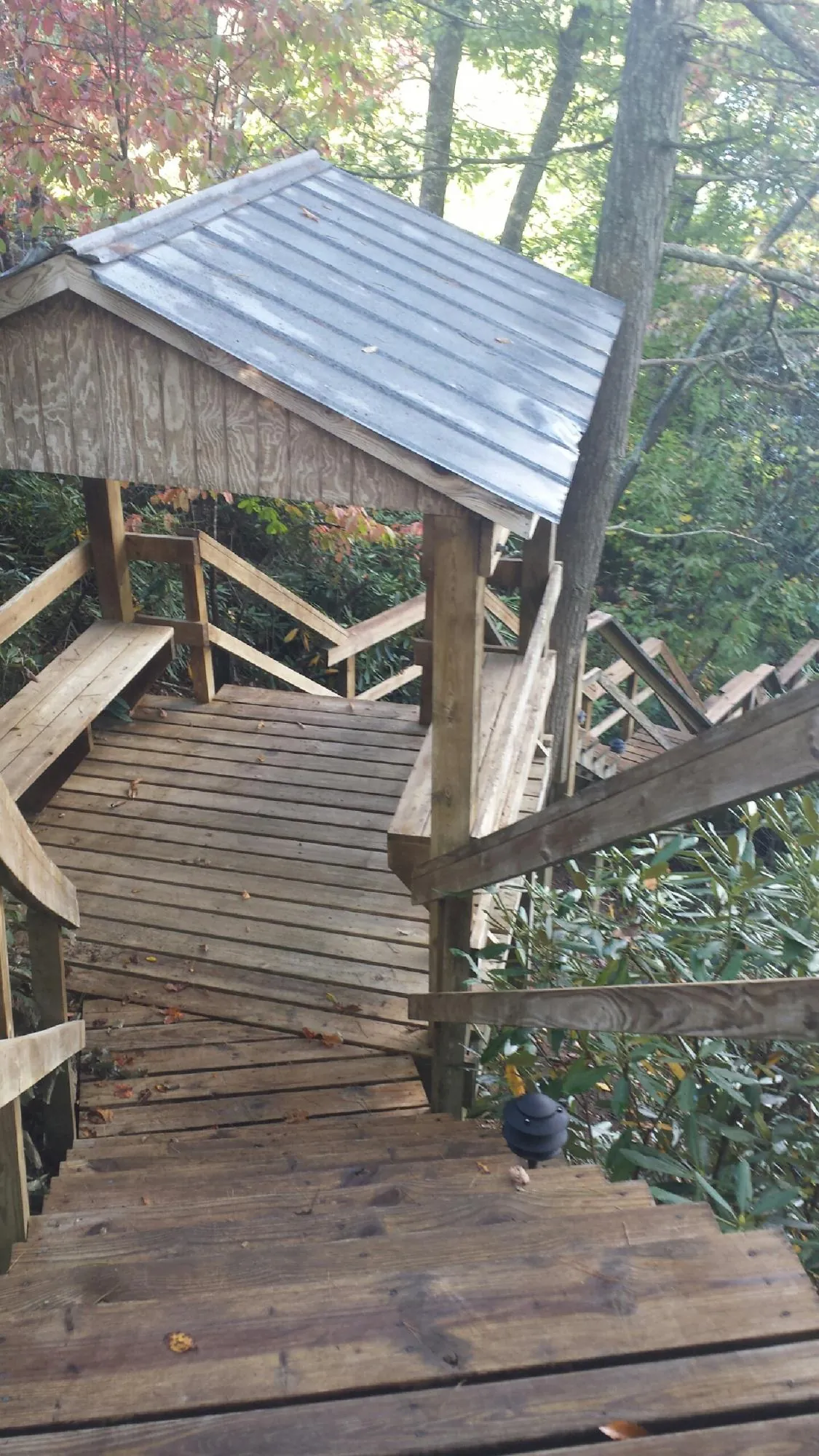 Metal roofed shelter over wooden steps on a wooded walkway — Skylight Repair & Installation work by our crew in Newton Falls