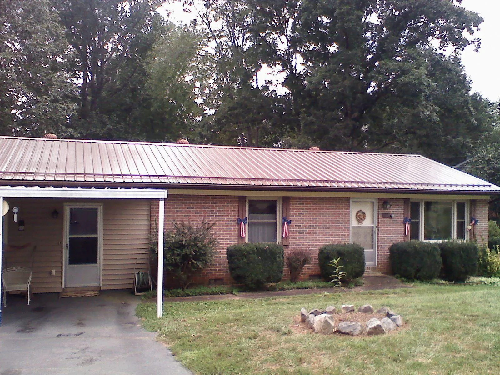 Bronze metal roof and carport on a brick ranch home — Roof Repair work by our crew in Newton Falls
