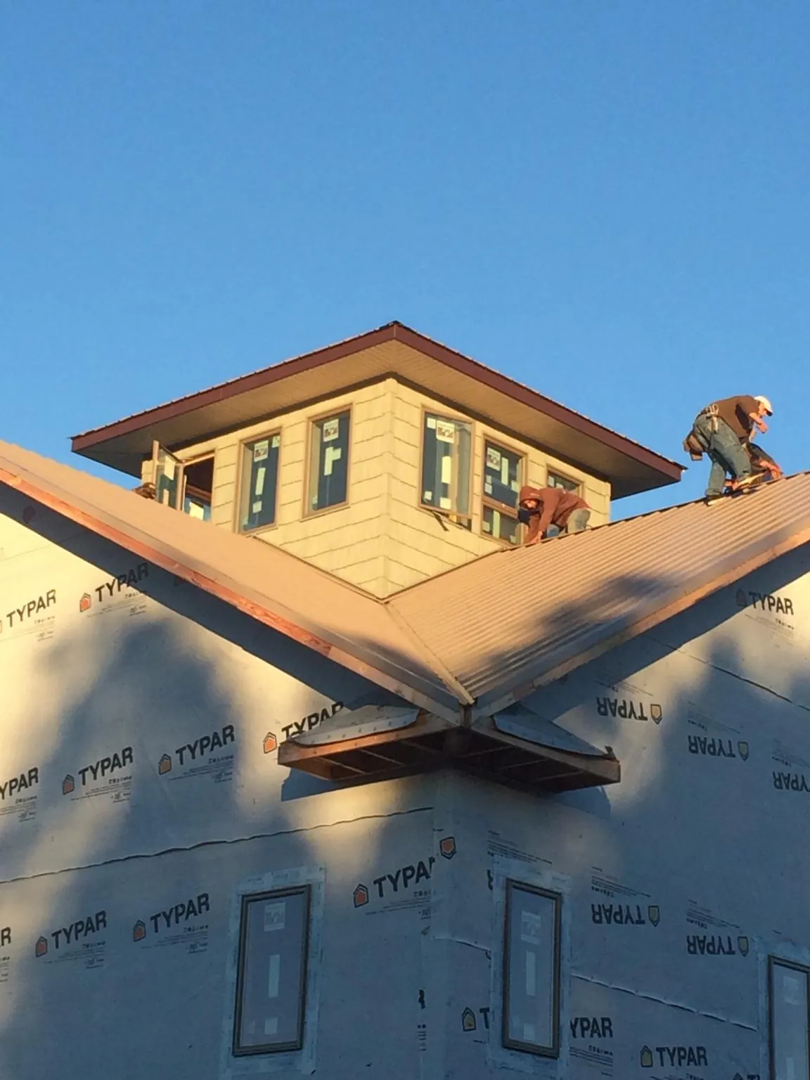 Roofers working around a rooftop cupola on a new metal roof at sunset — Roof Waterproofing in Newton Falls by Roofing Brothers